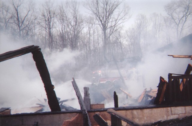 Behind the smoke, a firefighter hoses down the debris; 3 alarm house fire, Elwood Street in Salisbury Twp... 4/12/04